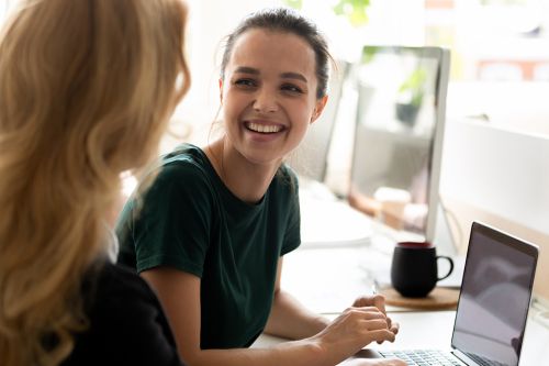 Frauen arbeiten am Laptop und lächeln